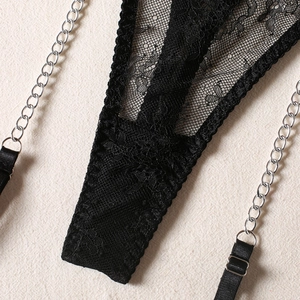 Detail of black floral lace lingerie with adjustable straps and decorative silver metal chain