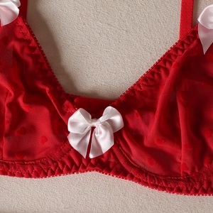 Detail of red mesh bra with heart patterns and white satin bows on the cups