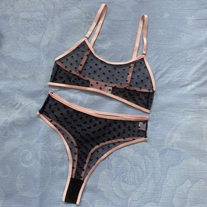 Detail of sheer polka dot mesh lingerie set with pink contrast trim and lace-up bra