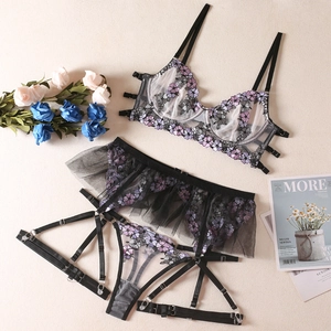 Détail de broderies florales violettes sur ensemble de lingerie en résille noire