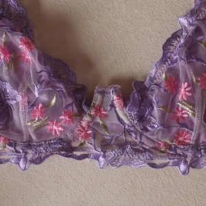 Gros plan sur un soutien-gorge en maille violette avec broderies de fleurs roses et d'or