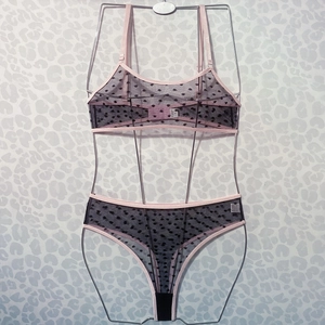 Detail of sheer black mesh lingerie set with polka dots and pink elastic trim highlights