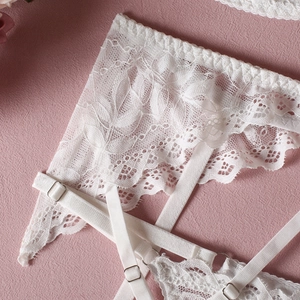 Close-up of white floral lace texture with elastic straps and silver metal buckles