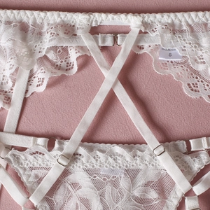 Close-up of white floral lace lingerie set with elastic straps and S size tag detail