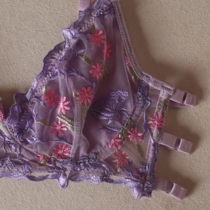 Détails de broderie florale rose sur lingerie en résille violette avec dentelle fine