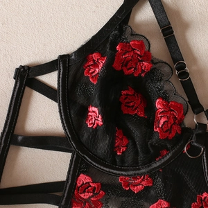Détail de broderie rose rouge sur soutien-gorge dentelle noire avec maille et anneaux