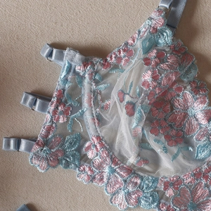 Close-up of light blue floral embroidery on sheer mesh lingerie with satin straps