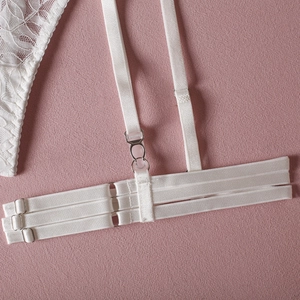 Detailed view of white floral lace fabric and elastic straps with metal adjusters