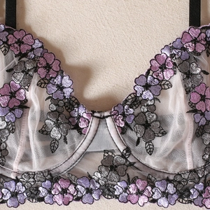 Détails de broderies florales violettes et argentées sur lingerie en tulle rose