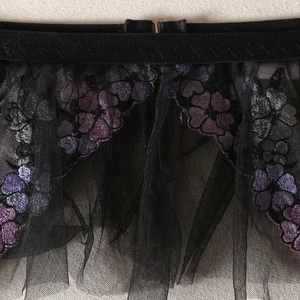 Détail de broderie florale sur lingerie en maille noire transparente avec crochet réglable