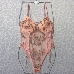 Close-up of pink butterfly embroidery and lace details on a sheer mesh bodysuit