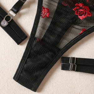 Détail de maille noire avec broderie de roses rouges et boucles métalliques réglables