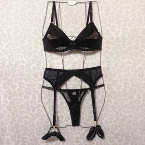 Three-piece black lace lingerie set with polka dots and garters on metal display