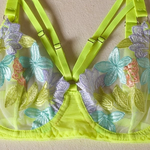 Detailed close-up of neon lace lingerie with vibrant floral embroidery and adjustable straps