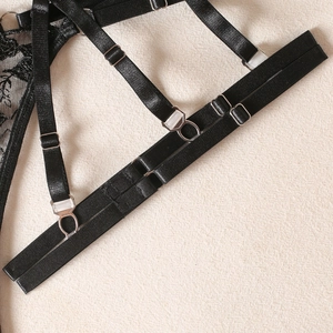 Detail of black lace garter belt with adjustable satin straps and silver metal buckles