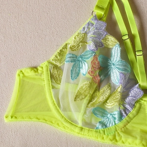 Detail of neon green lace bra with colorful floral embroidery and mesh texture