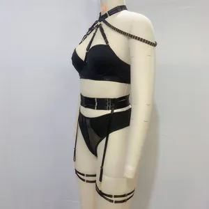 Detail of black lingerie set with golden chain harnesses and straps on a mannequin