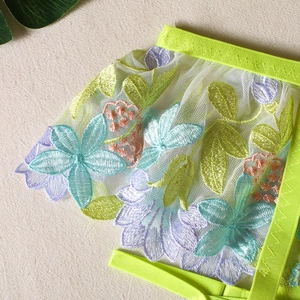 Close-up of floral embroidery on white mesh with vibrant neon green elastic straps