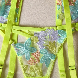 Detail of floral embroidery on neon green lingerie with mesh lining and metal buckles