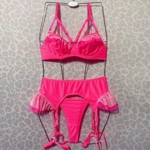 Ensemble de lingerie rose fluo trois pièces avec froufrous et porte-jarretelles sur cintre