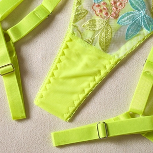 Detailed close-up of floral embroidery on neon green mesh lingerie with adjustable straps