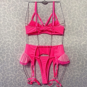 Détail d'un ensemble lingerie rose fluo avec dentelle à volants et soutien-gorge multi-sangles