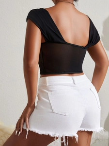 Detail of a black backless lace top with mesh splicing and white frayed denim shorts