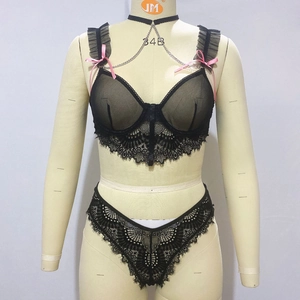 Detailed lace stitching on a black sheer mesh lingerie set with pink ribbon bows