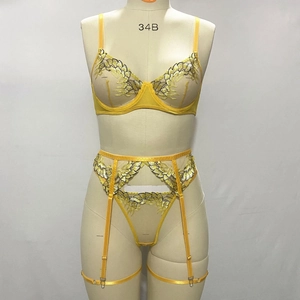 Detail of yellow floral lace embroidery on semi-sheer mesh lingerie with garter belt