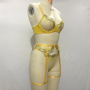 Close-up of yellow floral embroidery detail on sheer lace lingerie set with black piping