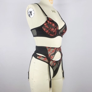 Détail d'un ensemble de lingerie en mesh noir avec broderie florale rouge et jarretelles