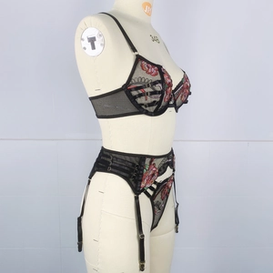 Detailed embroidery of red and green flowers on black lace lingerie with golden buckles