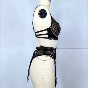 Detail of black lace bra with silver chain straps and adjustable garter belt on mannequin