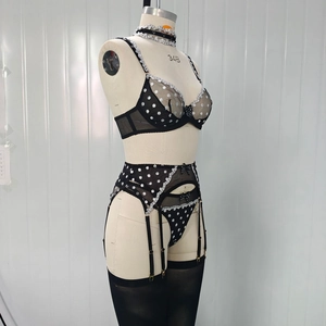 Detail of four-piece black polka dot mesh lingerie set with lace trim and bow accents