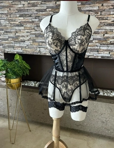 Detailed view of black lace bustier with intricate floral embroidery and garter straps