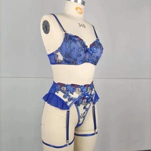Détail de la broderie florale sur soutien-gorge en résille bleue avec jarretière