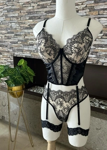 Detailed view of black floral lace bustier set with garter belt on a mannequin