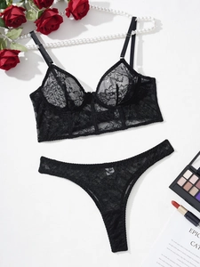 Detailed flat lay of black floral lace lingerie set with elegant roses and pearls