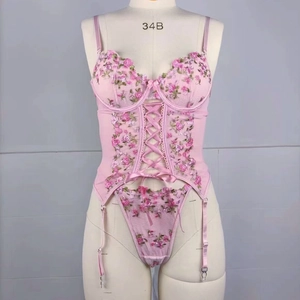 Détail d'un bustier en résille rose avec broderies florales et laçage croisé au centre