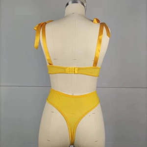 Detail view of bright yellow floral embroidery and mesh back on the sexy bodysuit