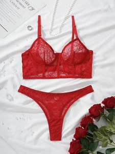 Flat lay of red floral lace bra and thong set with steel bone support on white fabric
