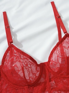 Macro detail of red floral lace bra showing sheer fabric texture and adjustable straps