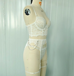 Detail of white lace lingerie set featuring pearl chains and adjustable garter straps