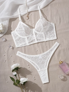 Flat lay of white lace lingerie set with floral embroidery and elegant accessories