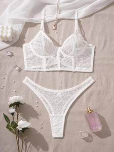 Flat lay detail of a white floral lace lingerie set with fine embroidery and matching thong
