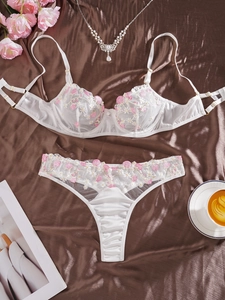 Détail de la broderie florale blanche et dentelle délicate sur l'ensemble soutien-gorge
