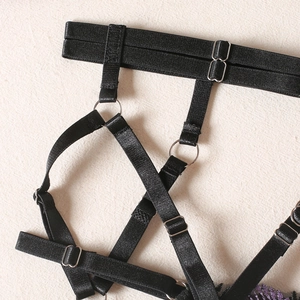 Detail of black elastic body harness with silver metal rings and purple embroidery accents