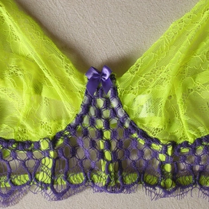 Detail of neon green lace bra with purple satin bow and floral embroidery textures