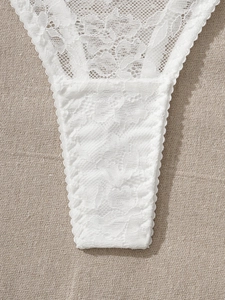 Close-up detail of white floral lace embroidery and sheer mesh on sexy lingerie set