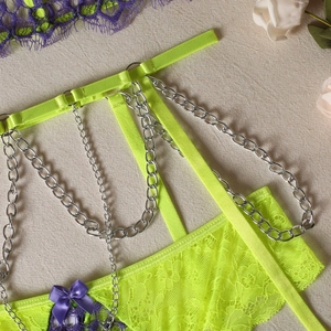 Detail of neon green lace lingerie featuring purple bows and decorative silver chains